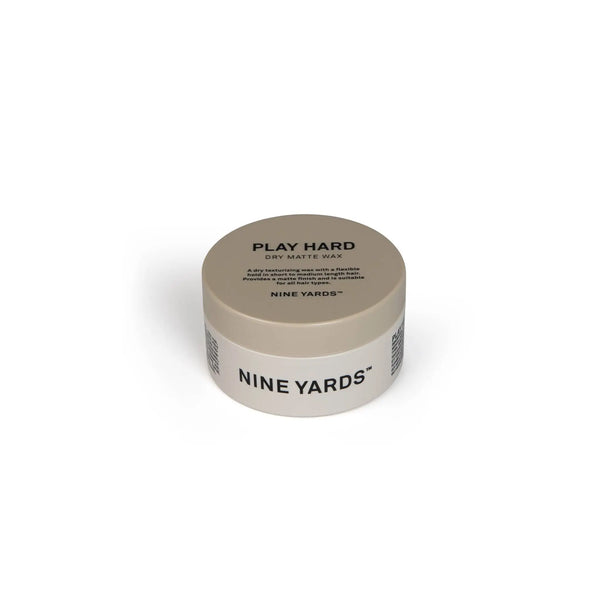 Smėlio spalvos apvalus NINE YARDS Play Hard Dry Matte Wax sauso matinio vaško indelis 100ml plokščiu dangteliu. Produkto pavadinimas aiškiai rodomas paryškintu juodu tekstu, atsižvelgiant į paprastą ir klasikinį dizainą, pastatytą baltame fone.